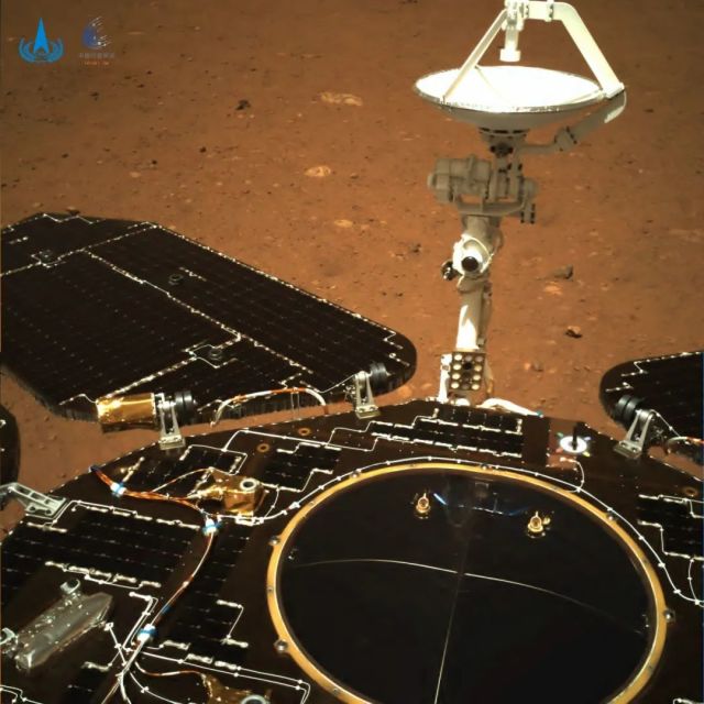 Цветной снимок Марса, сделанный задней камерой ровера. Видна антенна марсохода и его солнечные панели.