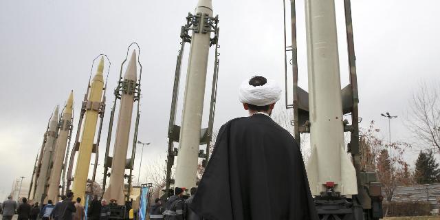 Иранский священнослужитель смотрит на ракеты класса земля – земля, продемонстрированные Корпусом стражей исламской революции на военном шоу, посвященном 40-летию Исламской революции
