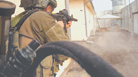 Израильский боец морского спецназа 13-й флотилии ведет стрельбу в кибуце Суфа на юге страны. Кадр из видео Reuters