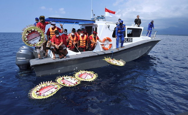 Люди бросают цветы с именами членов экипажа затонувшей подводной лодки Nanggala-402 во время молитвы на море