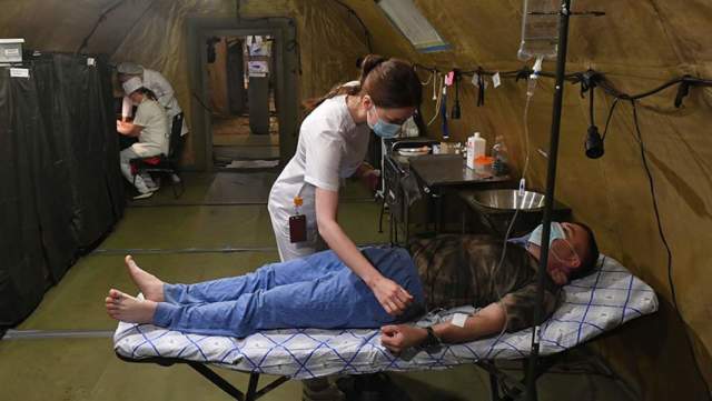 Медик и военнослужащий в палатке полевого госпиталя в зоне специальной военной операции