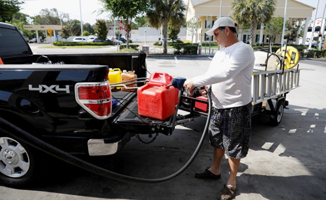 Мужчина наполняет канистры бензином на одной из немногочисленных работающих после кибератаки на трубопровод АЗС во Флориде, США