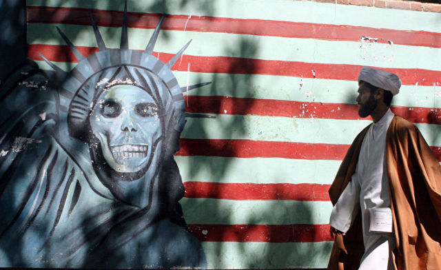 Мужчина на фоне граффити на стенах бывшего посольства США в Тегеране, Иран