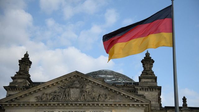 Национальный флаг Федеративной Республики Германии над зданием Будестага в Берлине