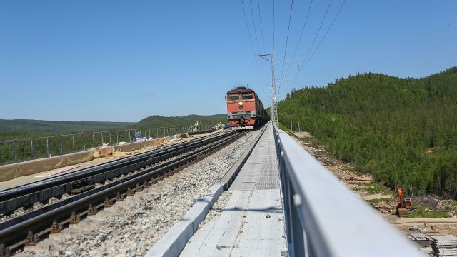 Поезд едет по реконструируемому в рамках строительства второй очереди Байкало-Амурской магистрали железнодорожному мосту через реку Кованта