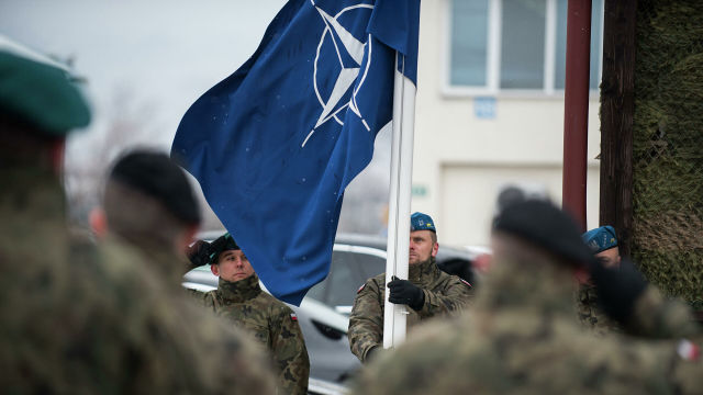 Польские военнослужащие поднимают флаг НАТО во время торжественной церемонии празднования 20-летия присоединения Чехии, Венгрии и Польши к блоку