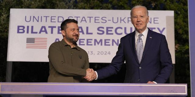 Президент Джо Байден и Владимир Зеленский пожимают друг другу руки после подписания двустороннего соглашения о безопасности на полях саммита G7 в Италии