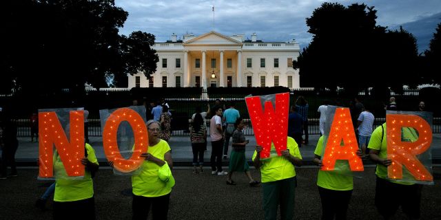 Протестующие с надписью нет войне у Белого дома в Вашингтоне