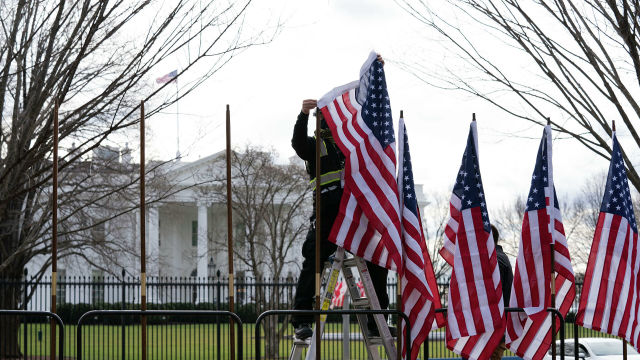 Рабочий устанавливает флаги возле Белого дома в Вашингтоне