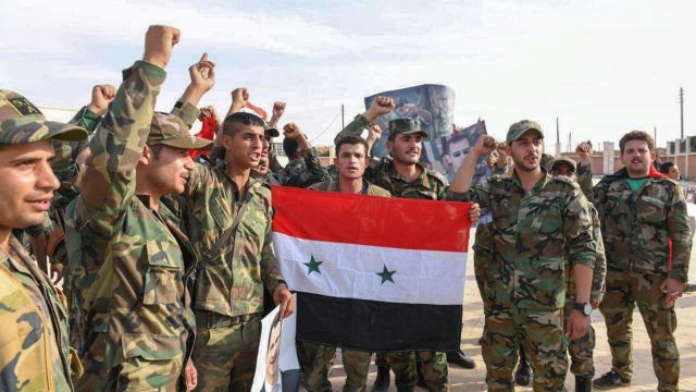 Сирийские военные с национальным флагом страны. Архивное фото