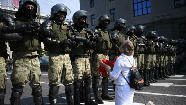 Участница акции протеста и сотрудники правоохранительных органов на проспекте Независимости в Минске