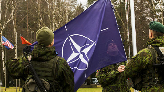 Военнослужащие поднимают флаг НАТО
