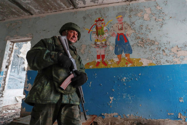 Военнослужащий Народной милиции ЛНР патрулирует здание заброшенной школы недалеко от линии разграничения в поселке Молодежное, февраль 2022 года