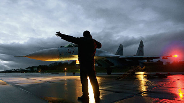 Военный техник дает отмашку на взлет истребителя Су-27