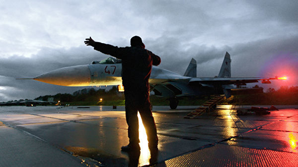 Военный техник дает отмашку на взлет истребителя Су-27 на аэродроме Чкаловск в Калининградской области