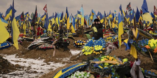 Женщина проходит между могилами солдат во время похорон Геннадия Ковшика, который был убит на передовой на востоке Украины. 16 февраля 2023 года
