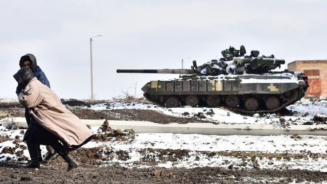 Жители Волновахи идут мимо подбитого танка ВСУ